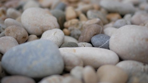 A man's hand puts a round sea stone on a pebble beach. Beautiful Pebble Beach. Marine Wave. Slow-motion.