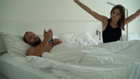 Young couple wakeup in the morning, turning off smartphone alarm clock