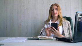 Young businesswoman talking on mobile phone and using laptop computer. Video chat job interview or distance language course class with online teacher concept