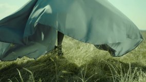 Rear view of woman's leg standing on field . Young stylish lonely girl stay on meadow field . Long skirt fabric flowing by wind in slow motion . Fashion style . Shot on ARRI Alexa Cinema Camera