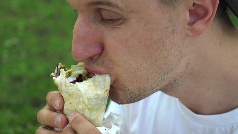 Man eating vegan wrap and licks his lips. Street food concept. 
