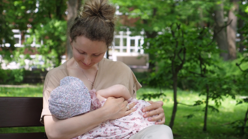 Young Mother Breastfeeding Her Baby in the Park.