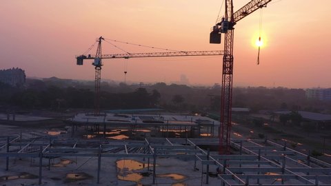 Aerial view from drone of construction site with cranes on sunrise sky background. Steel frame structure, structural steel beam build large buildings at construction site . construction machinery.
