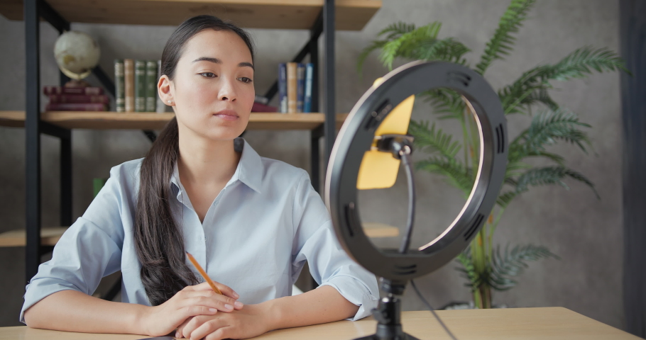 Close up portrait of smiling asian teacher conducts an online lesson using smartphone