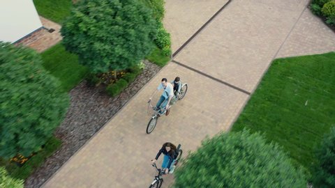 Family, mom, dad and two children ride a two-seater tandem bike along the beautiful deserted secluded park paths of an elite country village on self-isolation during the COVID-19 quarantine