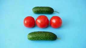 fresh organic cucumbers and tomato dance on blue background, creative video, stop motion animation, time lapse