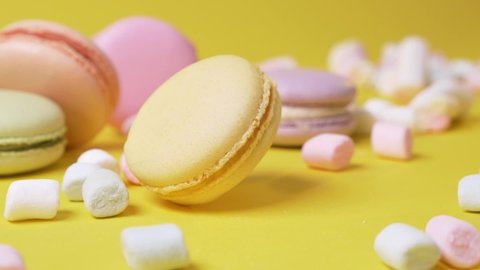 Sweet macarone to spin on yellow background bakery food color sugar pearl french dessert delicious table macaroon slow motion