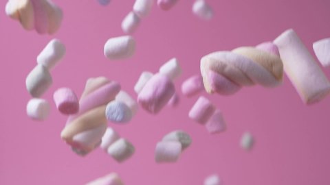 Soft and delicious colorful marshmallows soft sweet candie treats falling down isolated on bright pink background. Dessert. Sweet snacks concept.