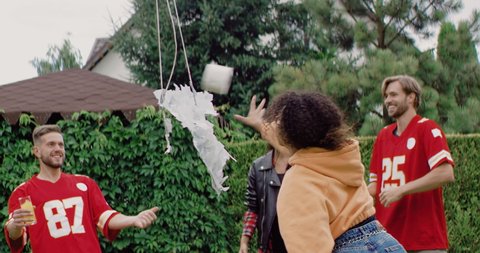 Diverse group of friends celebrating end of COVID-19 quarantine, picking up treats and toilet paper from destroyed coronavirus shaped piñata. Shot on RED cinema camera in slow motion