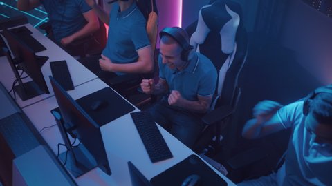 Diverse eSport Team of Pro Gamers Play in Computer Video Game on a Championship, Win and Celebrate. Stylish Neon Cyber Games Online Streaming Tournament Arena. Top Down View Gliding Dolly Shot