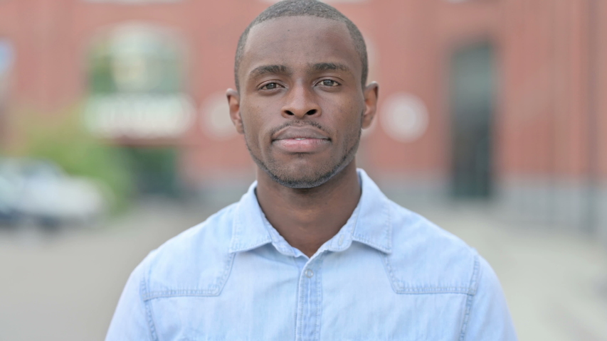 Outdoor Portrait of Disappointed African Man doing Thumbs Down
