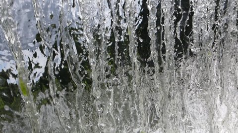 Video slow motion. Waterfall and fountain, water pours in a slow stream.