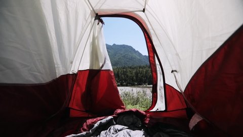 View from the inside of tent on mountain overlooking the river, scenery view on valley, forest and mountains at summer sunny day. Amazing view from tent in camping. Traveling, vacation concept.