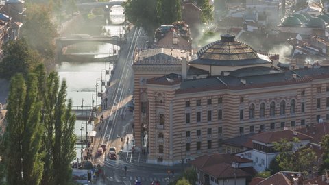 Panoramic aerial cityscape of the historical downtown of Sarajevo timelapse with City Hall, Bosnia and Herzegovina, with famous buildings and the bridges across Miljacka river before sunset from