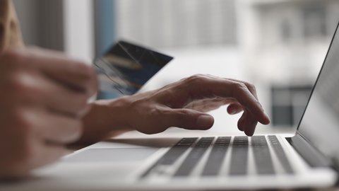 Close-up of the finger, Young man pressed the credit card code to pay online via the laptop at the desk in the room, Online purchases and use of credit cards concept.