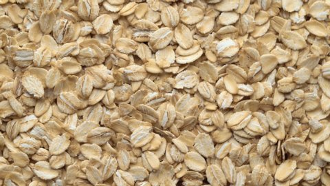 Oatmeal. Oat flakes. Close-up rotating. Dry oat flakes grains background, close up rotation loopable 4k top view. Food background. Gastronomy concept, organic food. Macro rotation oat flakes.