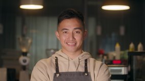 Successful small business korean owner man standing with crossed arms with employee in background preparing coffee. Portrait of asian young male cafe owner . - Powered by Shutterstock - Get 15% off with code: PIKWIZARD15