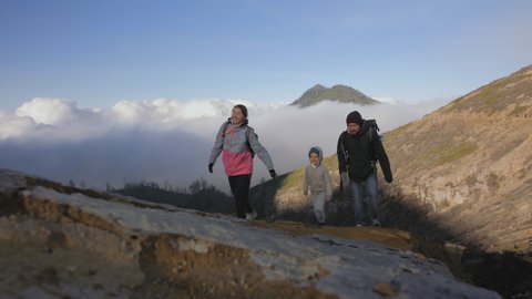 Young family with child during hiking on mountain. Hikers have adventure on volcano. Healthy active lifestyle. Breathing toxic air. Ecological problem. Environmental pollution, disaster