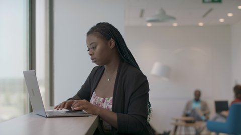Back at work at a technology firm. A  computer programer works on her laptop. Business is back. Shot in slow-motion and in 4k. 
