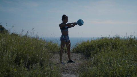 A powerful woman exercises on a hilltop in order to achieve her goals. Focused and determined. Shot in 4k. 