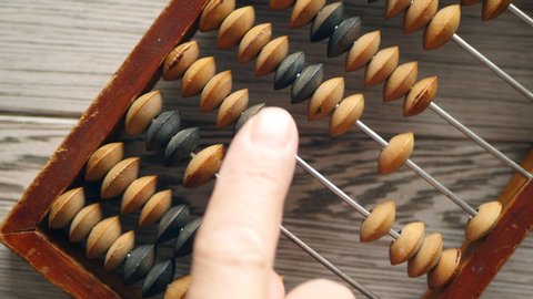 A Elderly Man Moves Wooden Knuckles On A Outdated Vintage Wooden Abacus On A Gray Desk, Close-up On The Right Side. Natural Daylight.