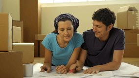 Young couple making projects in their new home, then smiling at camera;  HD: Photo JPEG
