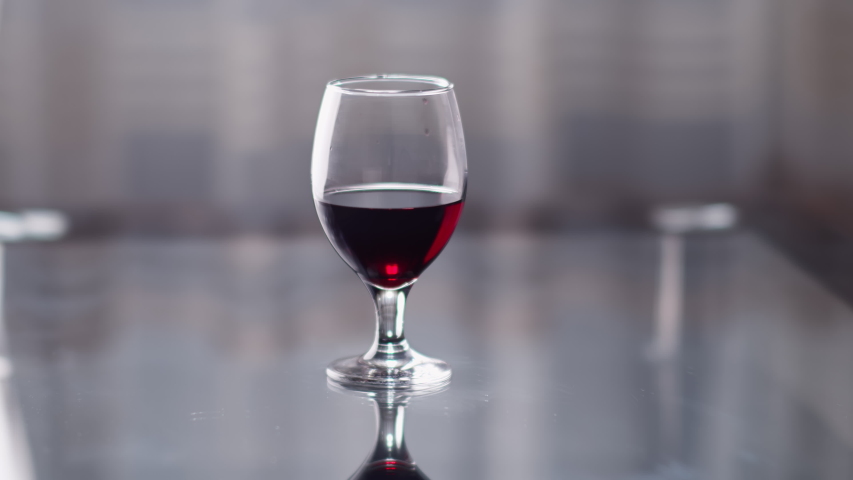 Graceful female hand takes a glass of red wine from the table, light background | Shutterstock HD Video #1056761975