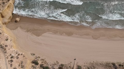 Aerial drone shot of waves moving towards Playa La Carolina beach, Murcia, Spain. High quality Full HD footage