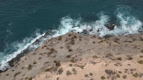 Aerial drone POV of waves breaking on cliff, Playa La Carolina, Murcia, a tourist destination in Spain. High quality Full HD footage