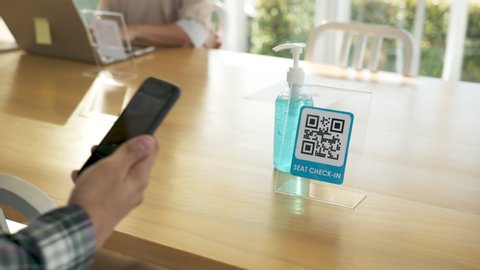 Asian man qr scan seat check in and hand sanitizer before start work at coworking space. Asia employee start work after covid loackdown measure. Shared and flexible office concept. Protection measure