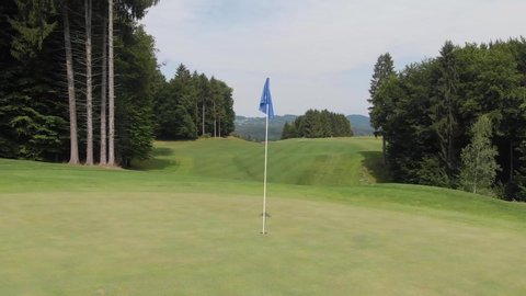 Blue flag in a golf hole on a beautiful golf course in the middle of the forest. Golf course in the countryside. Beautiful landscape of a golf court in Slovenia.