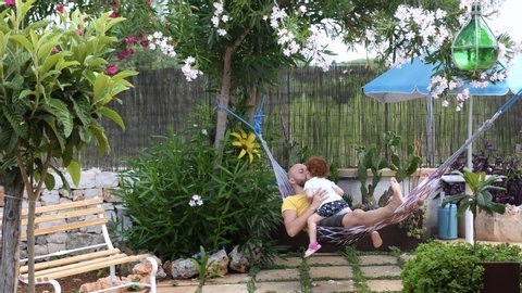 Dad and daughter swing on the hammock in the garden. scene of tenderness and love between father and daughter