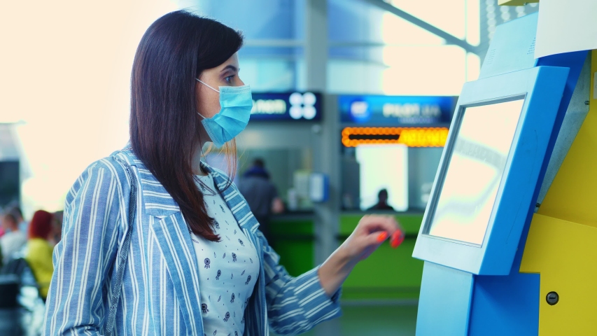 close-up, a young woman checks in on self check-in kiosk at the airport. air travel opening after coronavirus pandemic. Royalty-Free Stock Footage #1056770603
