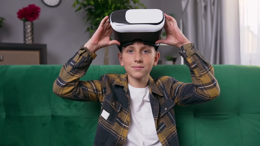 Good-looking confident modern teen boy applying augmented reality goggles while spending his leisure at home ,slow motion