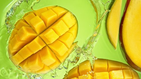 Super Slow Motion Shot of Mango Falling and Splashing into Water on Green Background at 1000fps.