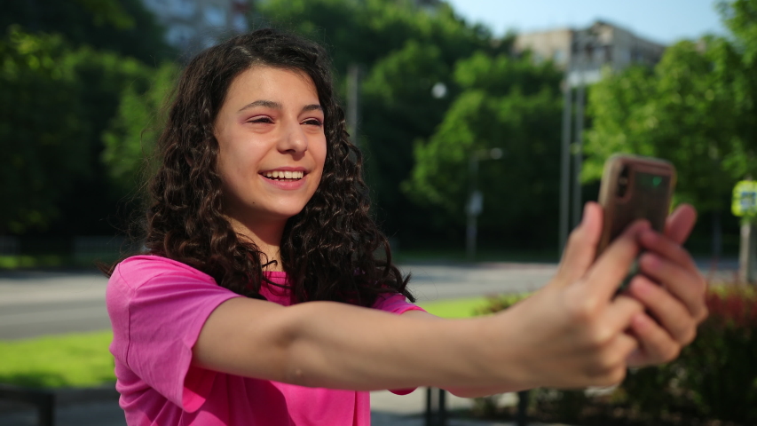 Portrait young girl of model appearance talking on the telephone. Female holds a mobile phone, talks via video link or takes selfie. Gal is speaking smartphone, baring her teeth, grin.