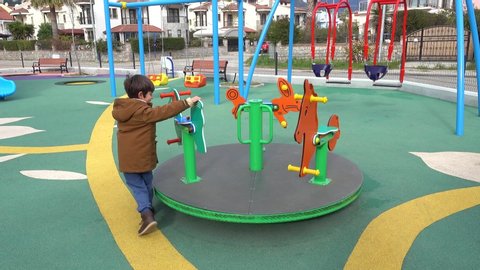 Fethiye, Turkey - 23d of November 2020: 4K Child rides merry-go-round playing alone on the children playground
