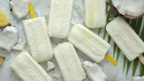 Summer popsicles on stick. Pinacolada flavour. Made with pineapple, cocount milk and rum. Vegan snack. Decorated with fresh fruit. Top view. Flat lay.