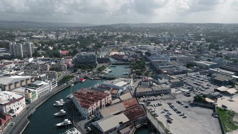 Aerial shot over the city, the river with white yacht and bridges with cars in Bridgetown, Barbados