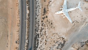 Abandoned airplane by the highway in the desert of Umm Al Quwain emirate of the United Arab Emirates aerial view at sunrise