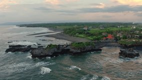 Aerial footage of black volcanic ocean beach with blue water, green rice terraces and beautiful villas. Travel concept, drone view. Bali, Indonesia