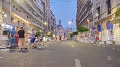 Day to night hyperlapse of car free boulevard Calea Victoriei in downtown Bucharest at Continental hotel, with pedestrians walking in the street. Bucharest, Romania - August 1, 2020.