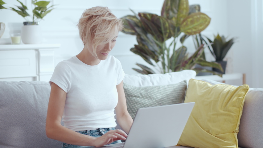 Young woman mother using laptop winning online prize sharing great news with family gathering on sofa celebrating exciting time. Families. Children.