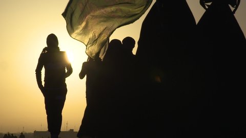 KARBALA, IRAQ - NOV 2017: Silhouette of crowd of pilgrims walking in Arbaeen pilgrimage at sunrise. Every year, millions of Shiite muslims come from all over the world to Karbala to walk Arbaeen