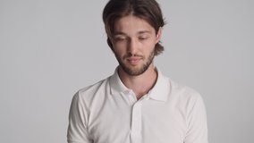 Young attractive brunette man trying to remember something tiredly looking in camera over gray background