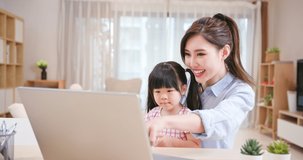 asian young woman and her daughter have video chat with computer happily