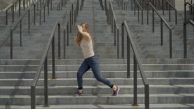 long shot 4K. Young lady contemporary dancer dancing on the steps on an industrial background. straight lines video.