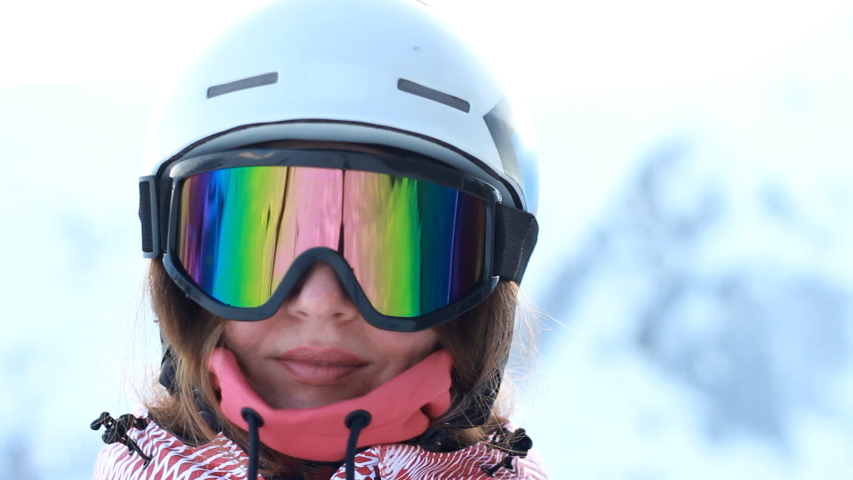 Close up portrait woman in a mask from the sun and a helmet is preparing for the descent in the mountains. Skiing or snowboarding. The concept of victory in sports, winning, win. Royalty-Free Stock Footage #1056828995