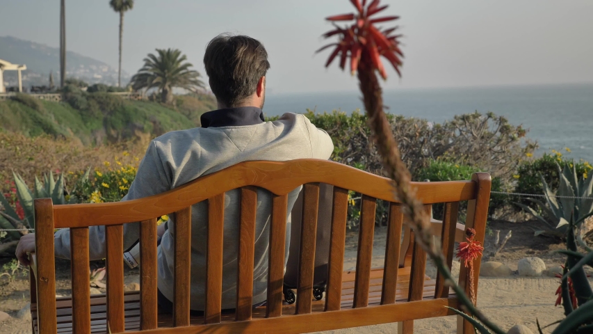 Men sits down on the bench at Laguna Beach admires the view scenic magnificent view
