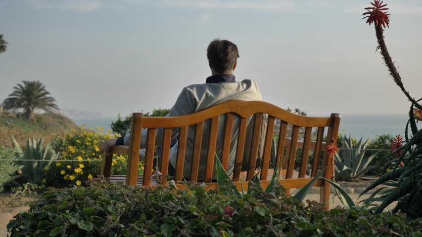 Men sits down on the bench at Laguna Beach low angle